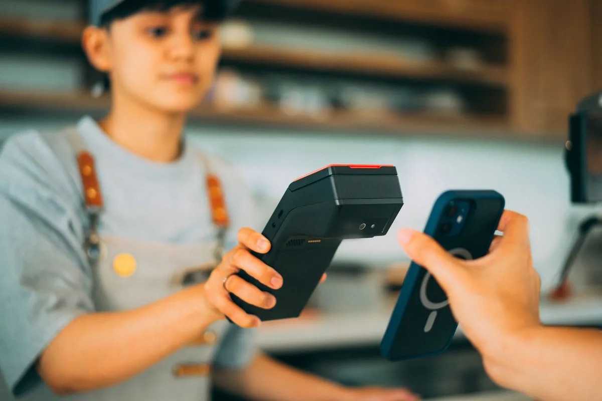 店员使用手持移动收款终端完成顾客手机付款
